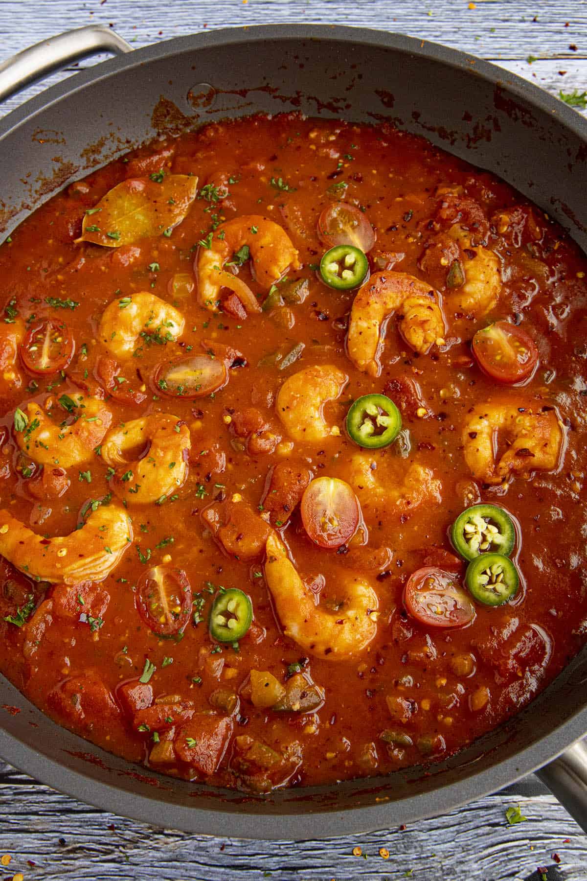 Shrimp Creole in a pan, garnished with peppers and chili flakes.