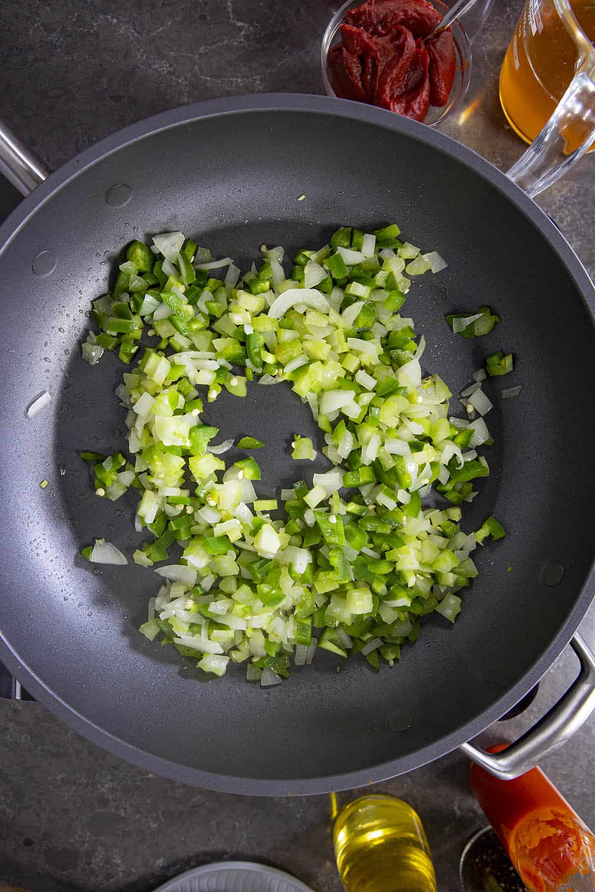 Cooking down peppers and onions in a pan.