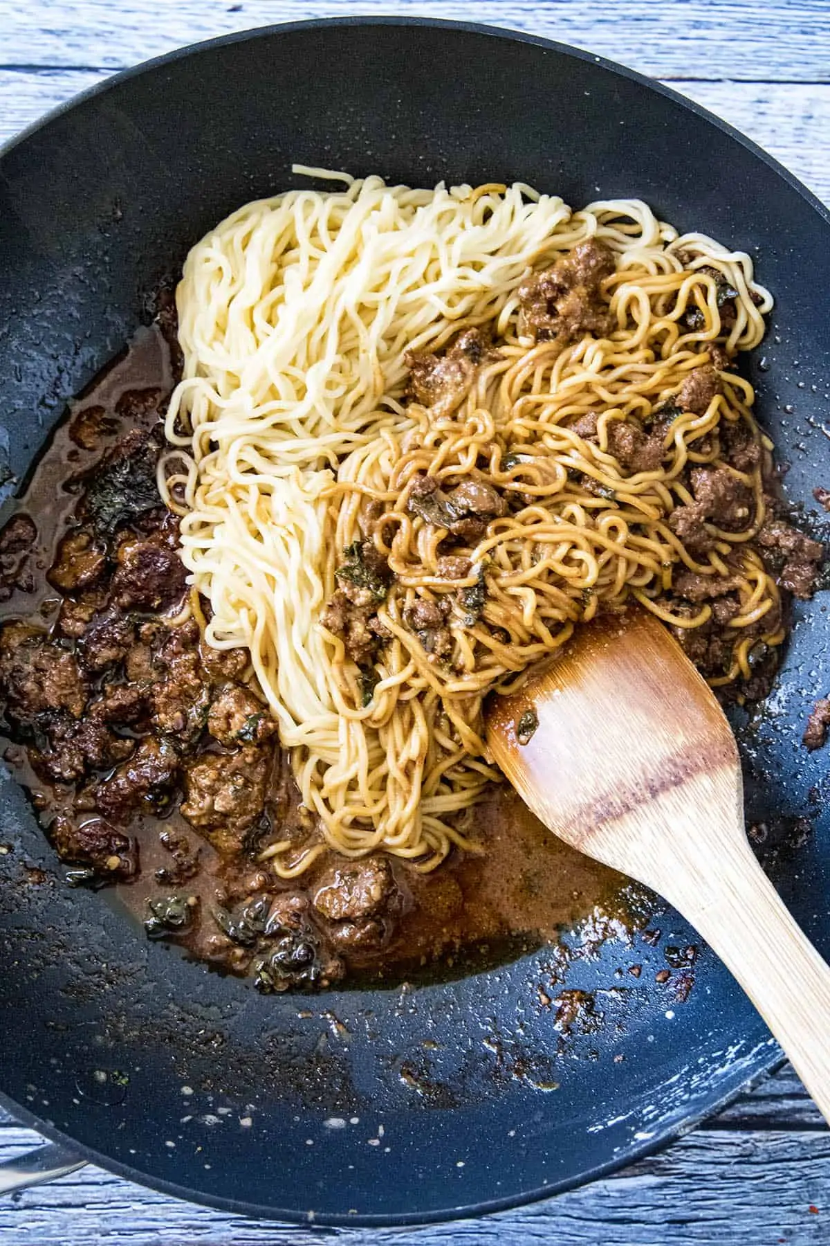 Mixing noodles and dan dan sauce to make dan dan noodles