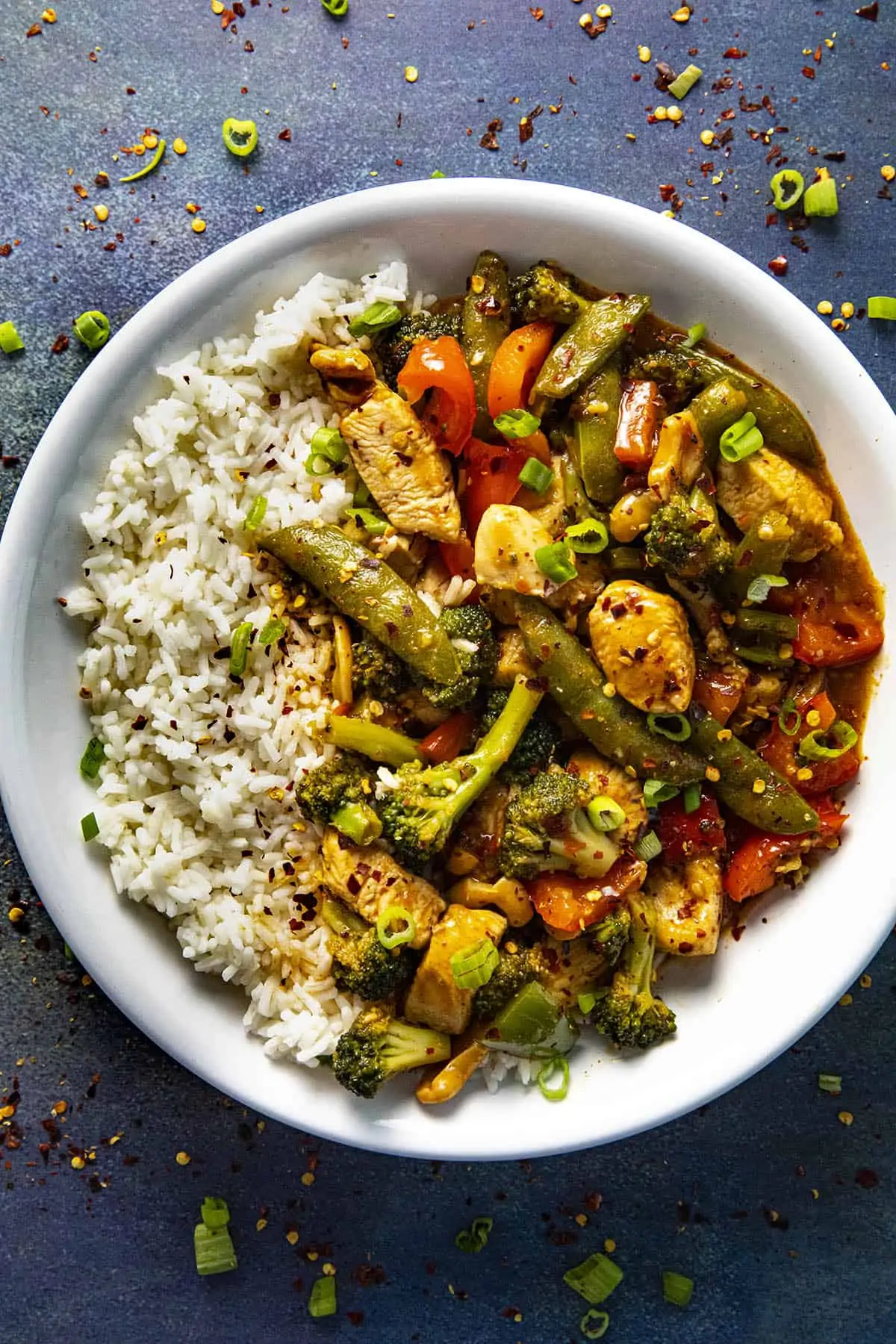 Chicken Stir Fry in a bowl with rice and spicy chili flakes.