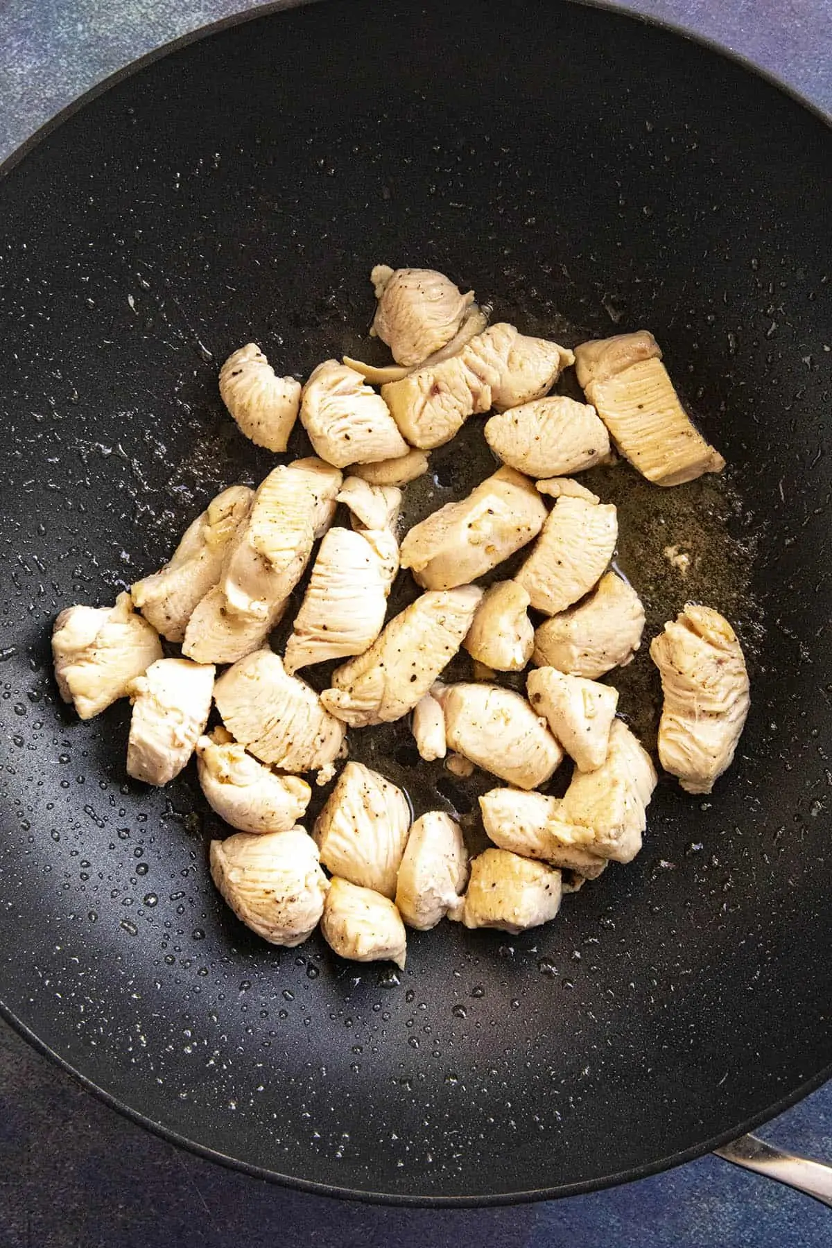 Stir frying the chicken in a hot pan.