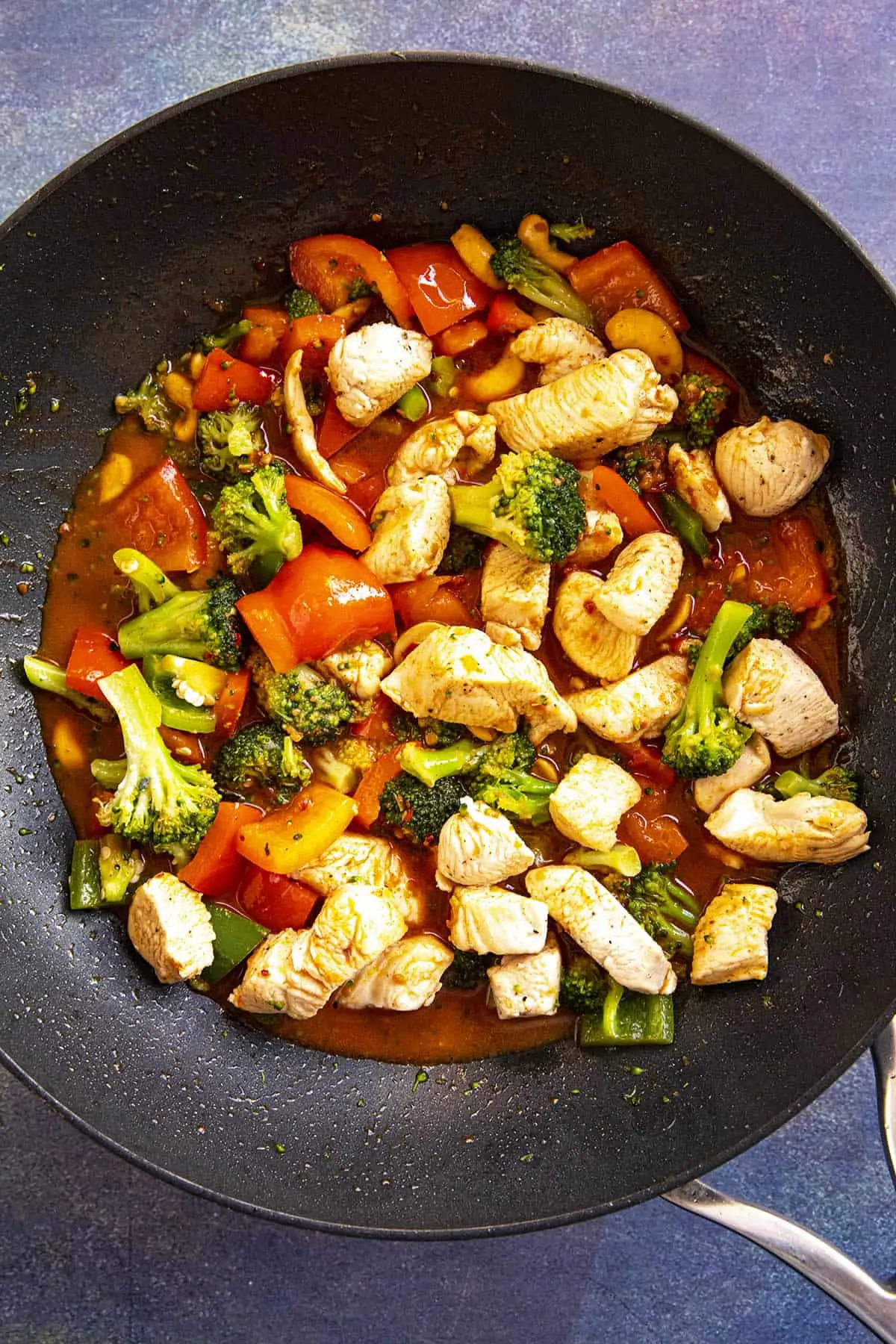 Mixing together chicken, vegetables and stir fry sauce in a hot pan.