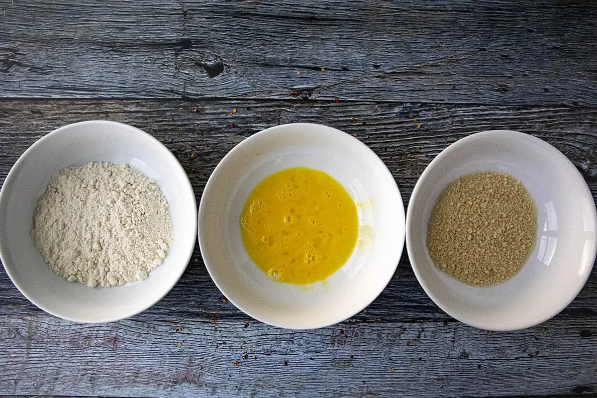 3 bowls set up for making pork katsu, with flour, scrambled egg, and panko.