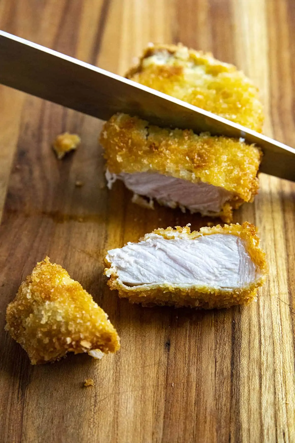 Mike slicing Pork Katsu on a cutting board.