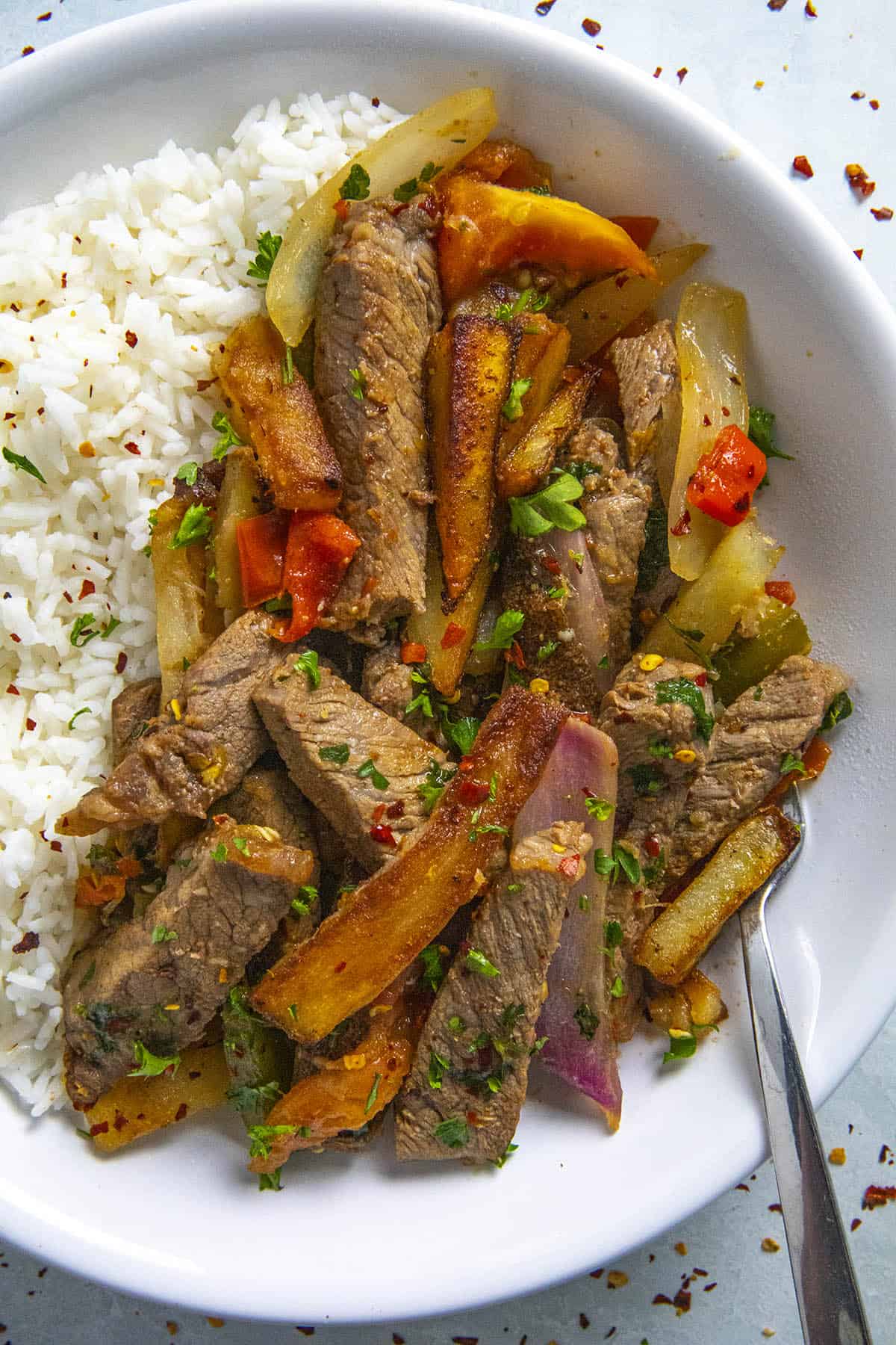 Peruvian Beef Stir Fry (Lomo Saltado) in a bow over rice with lots of beef and french fries