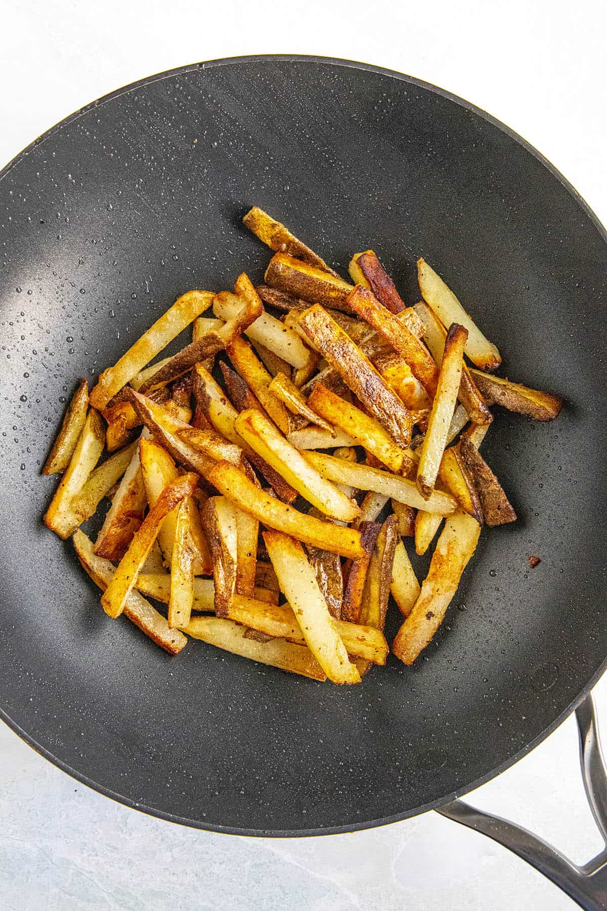 Stir frying the french fries in a hot pan with oil