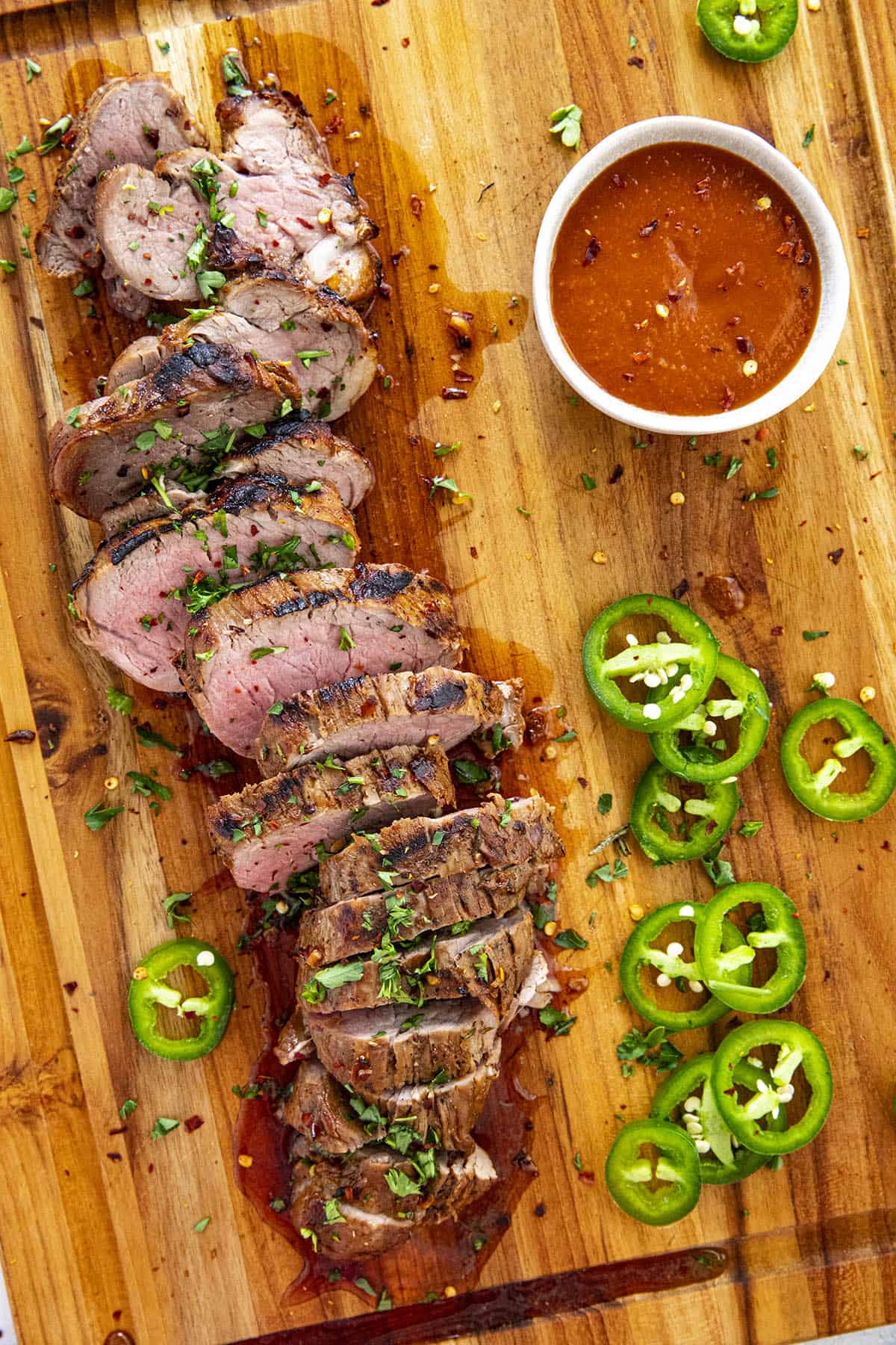 Sliced and grilled marinated pork tenderloin on a cutting board