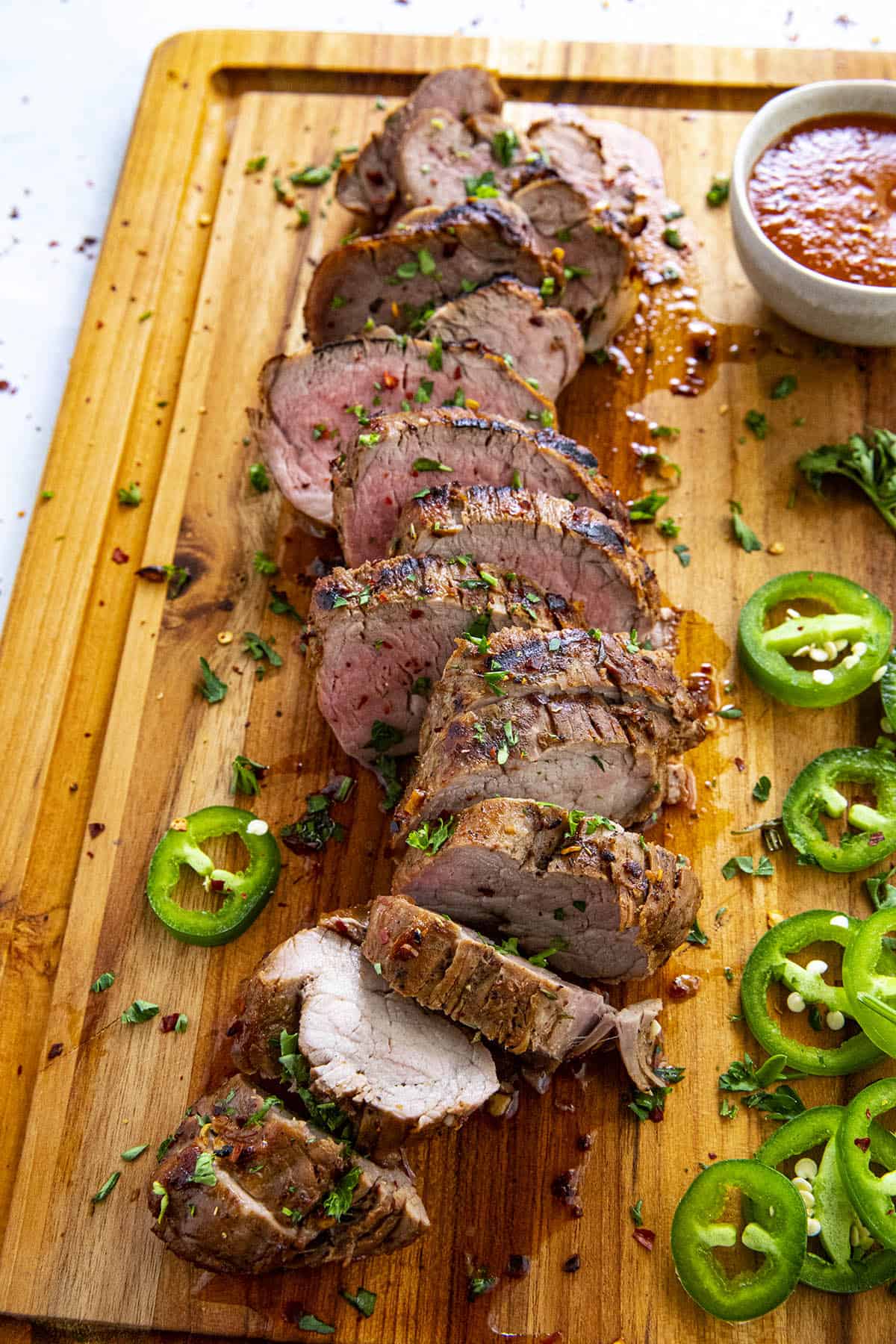 Sliced and grilled marinated pork tenderloin on a cutting board, ready to serve