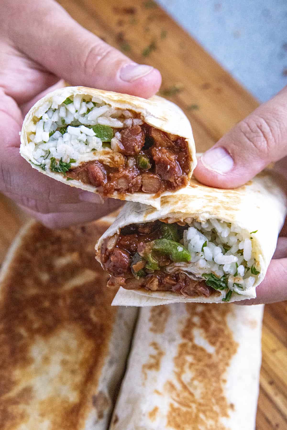 Mike holding a bean burrito in each hand.