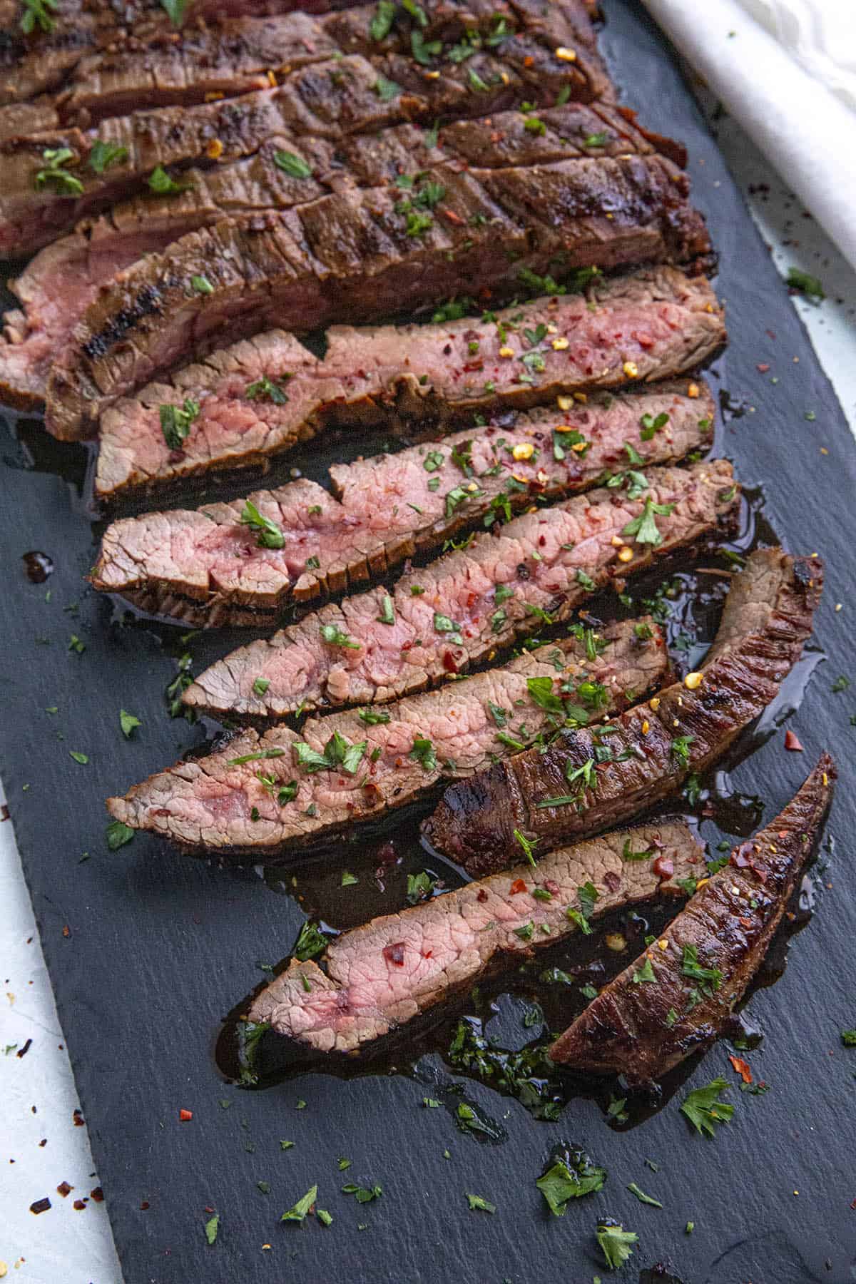 Sliced marinated flank steak on a cutting board