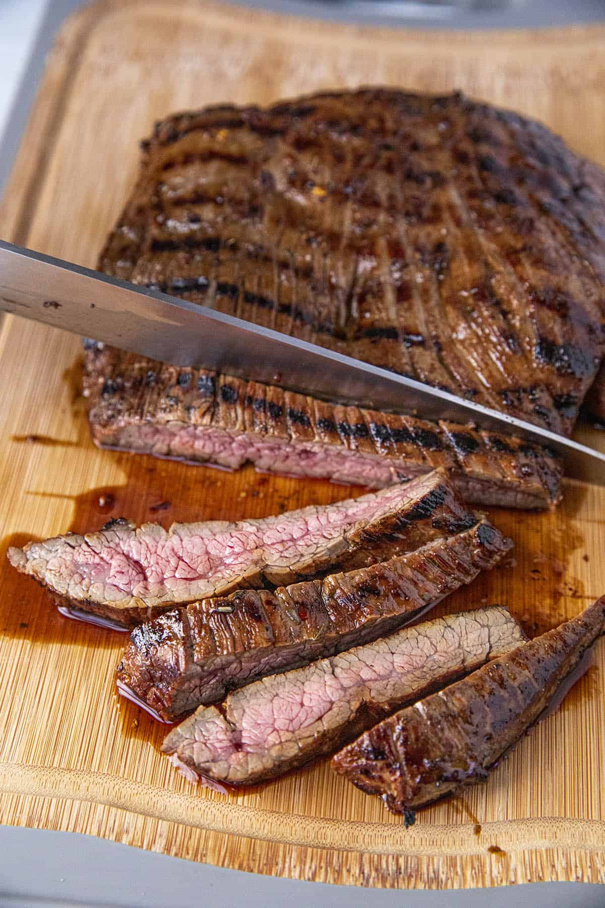 Slicing grilled marinated flank steak across the grain