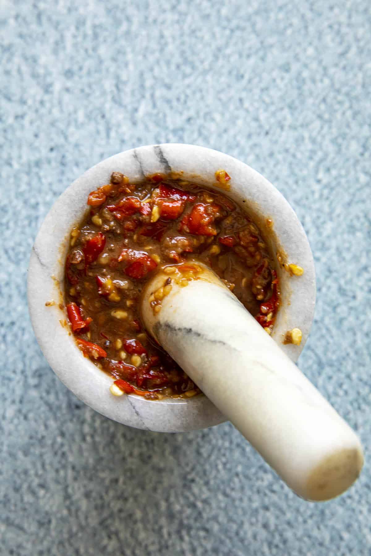 Sambal terasi in a mortar, being ground