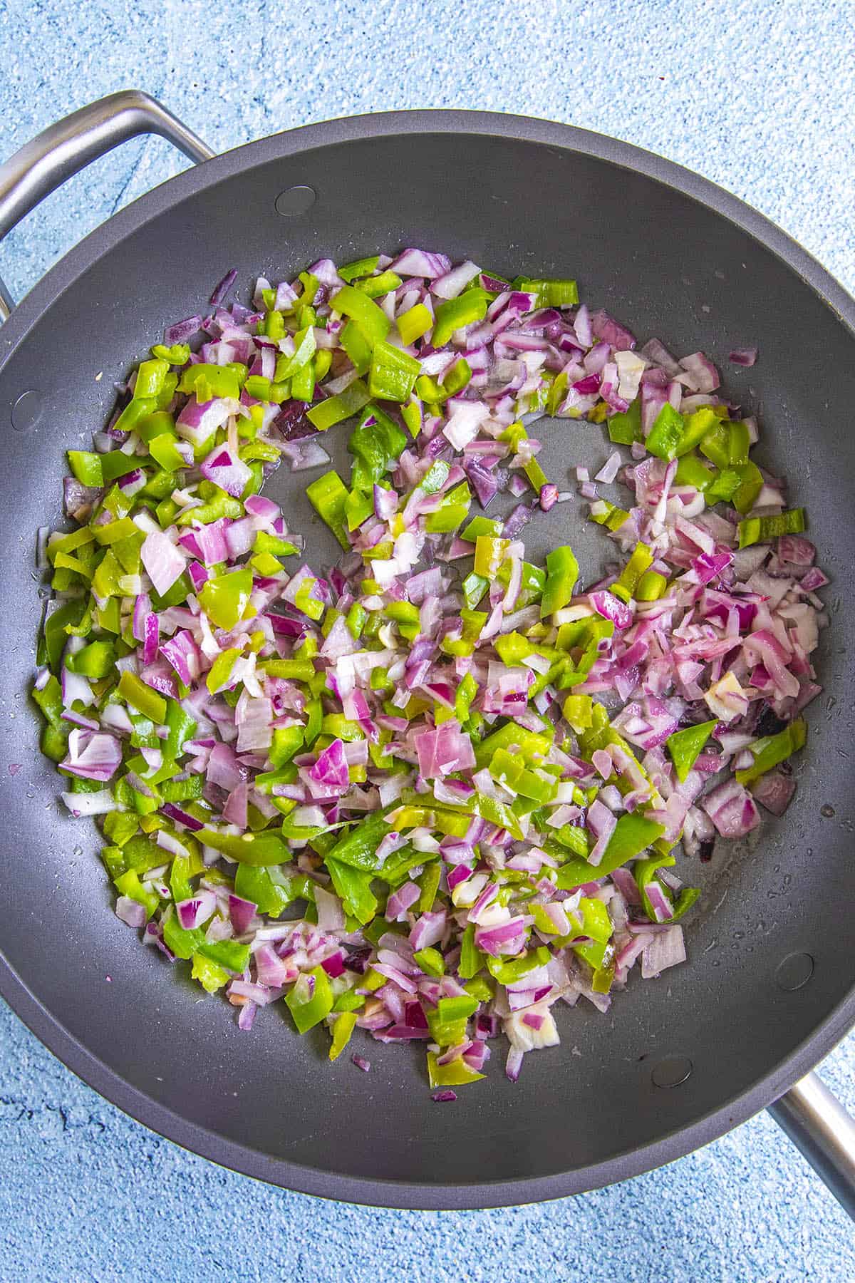 Cooking onion and peppers in a pan to make succotash
