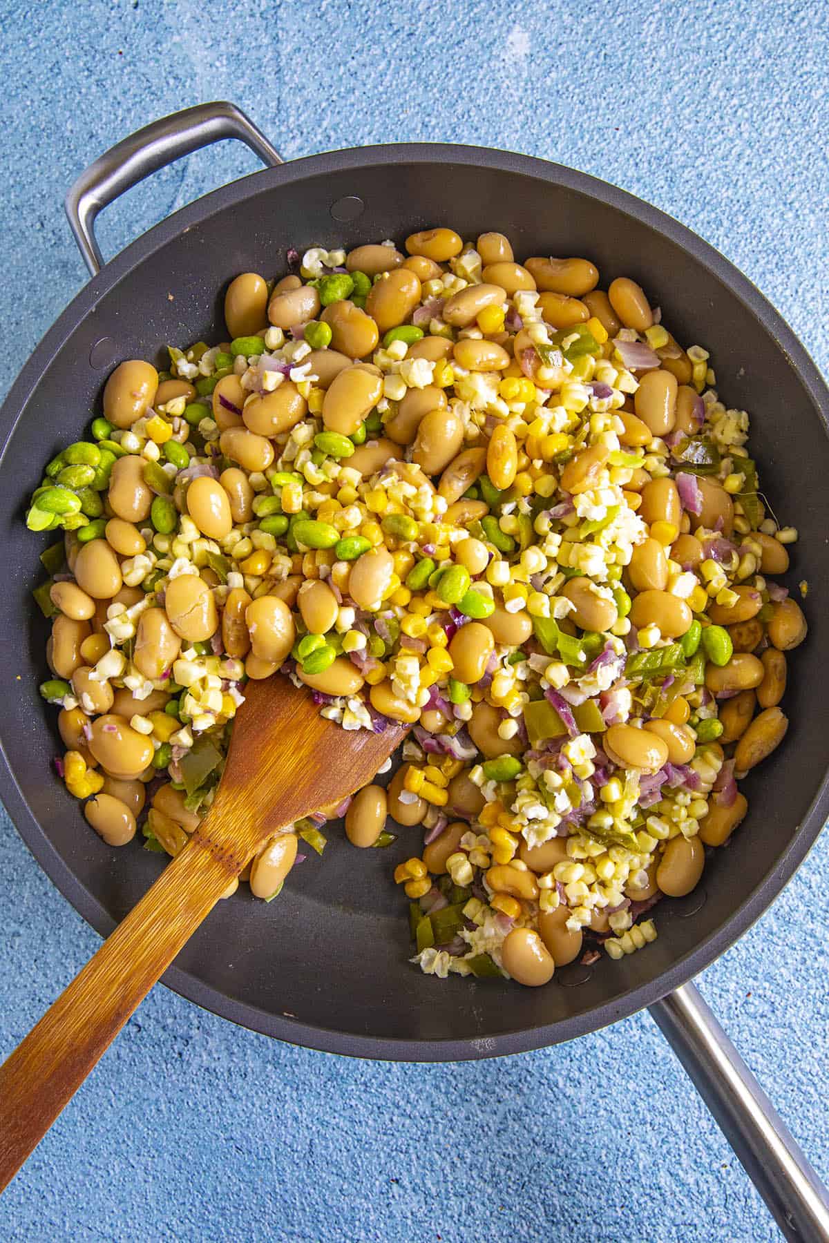 Stirring butter beans and corn into the succotash
