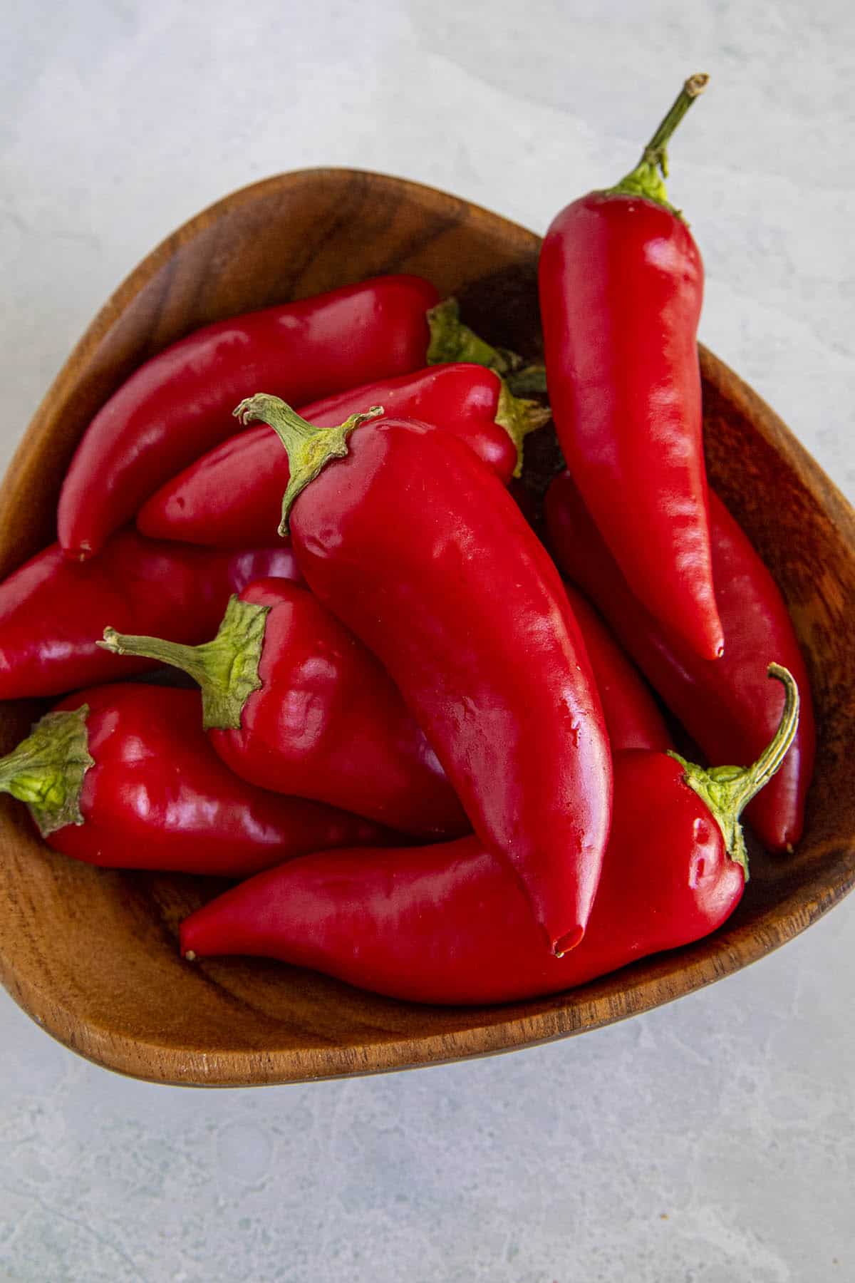 A bunch of spicy Fresno Peppers in a wooden bowl