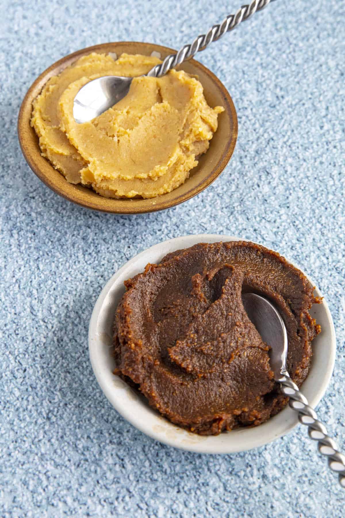 Two different bowls of miso paste with spoons