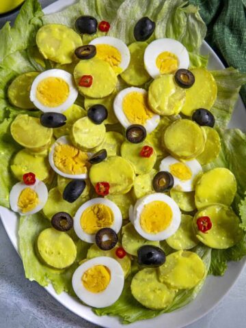 Papa a la Huancaina on a platter with sliced hard boiled eggs and black olives, served over lettuce