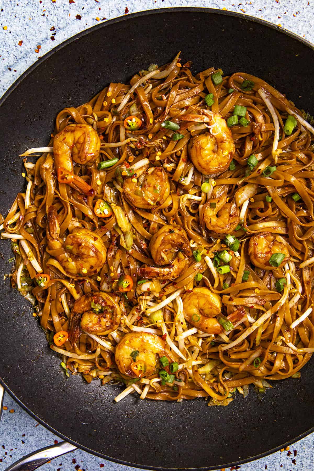 Mie Goreng, Indonesian stir fry noodles, in a hot pan with garnish