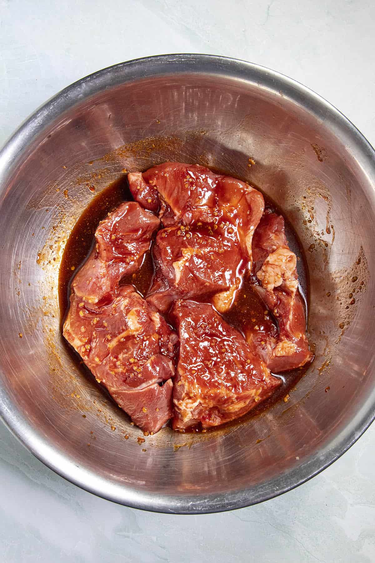 Marinating the chunks of pork in a bowl