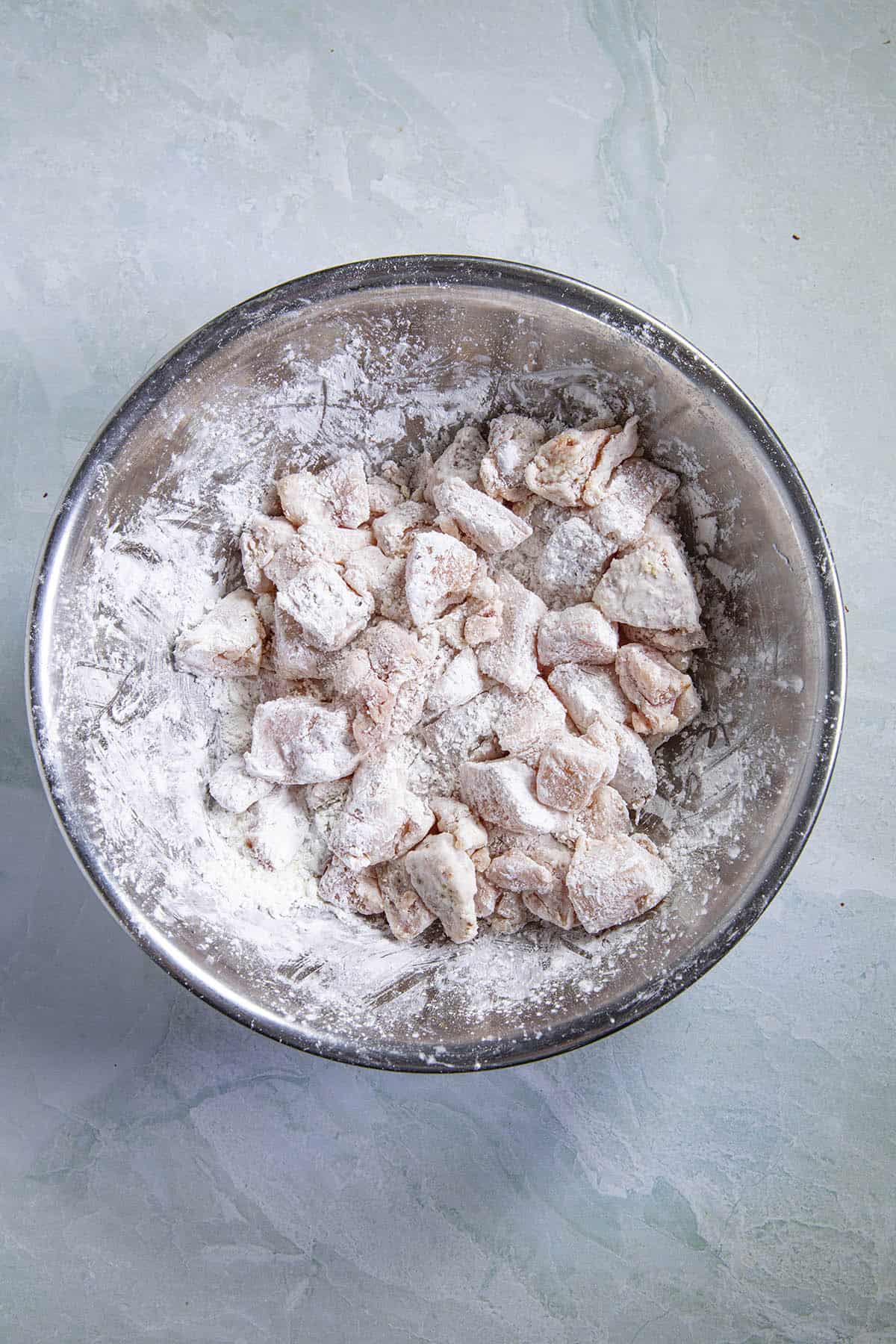 Coating chicken pieces in corn starch to make Hunan chicken