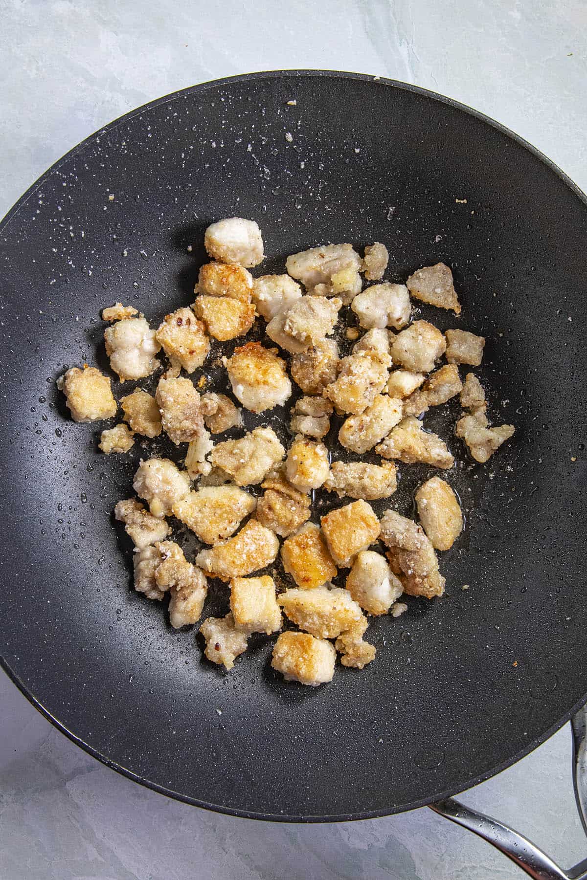 Frying the coated chicken in the hot pan to make Hunan chicken