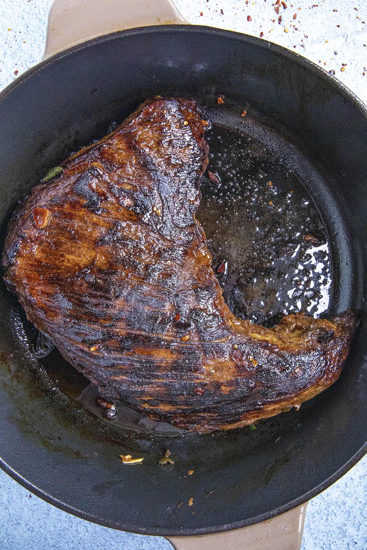 Searing the marinated tri tip in a cast iron pan