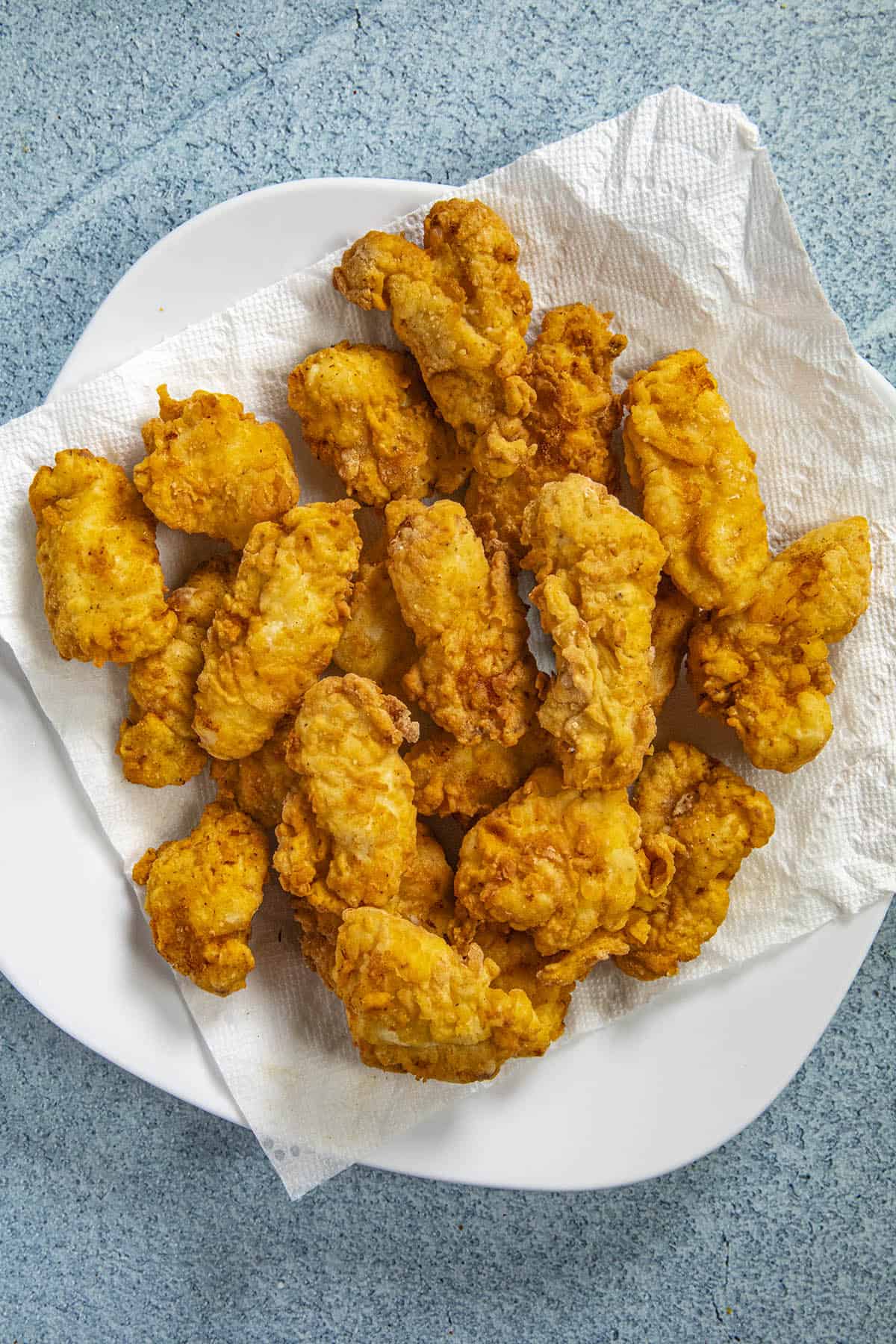 Draining the oil from the fried boneless wings on a platter