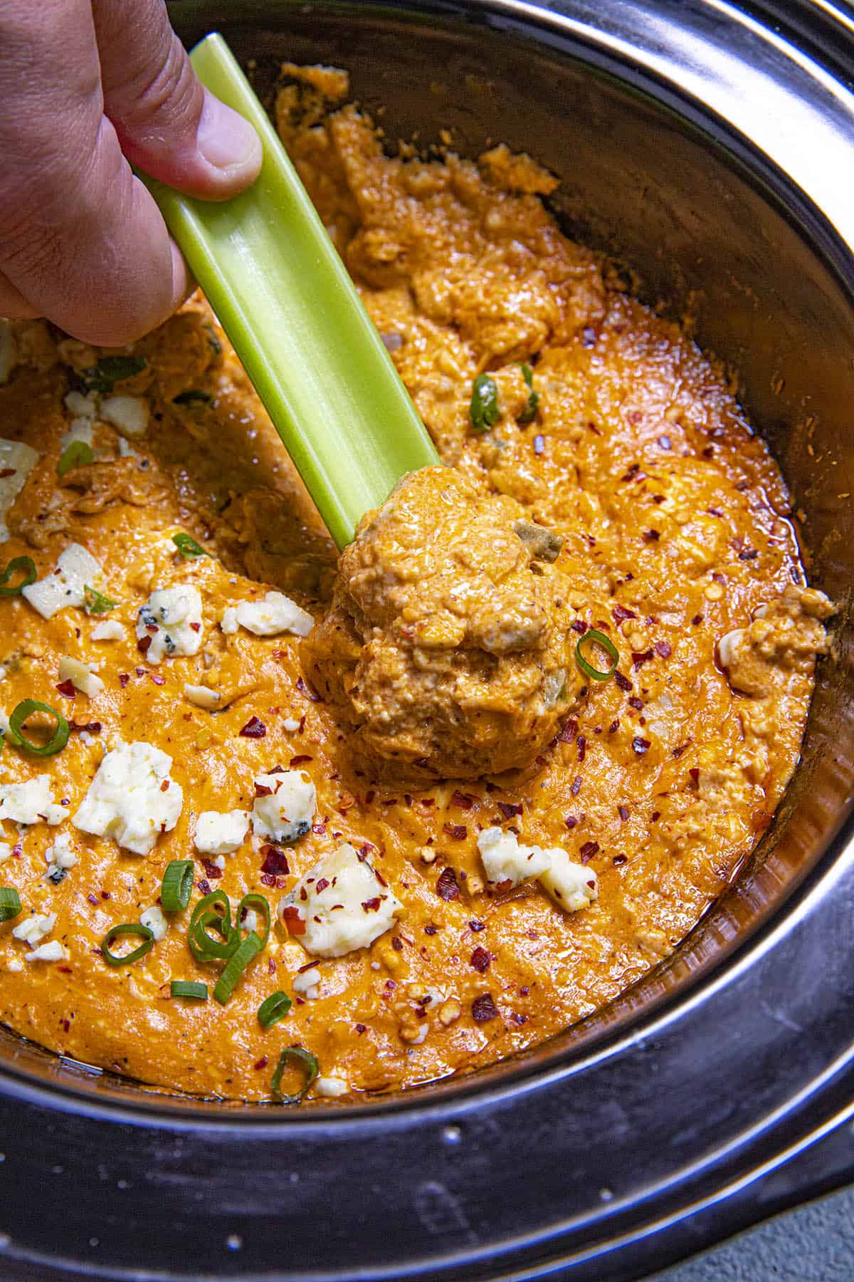 Mike taking a scoop of Crockpot Buffalo Chicken Dip with a celery stick