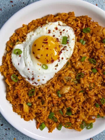 A beautiful fried egg on top of a bowl of spicy kimchi fried rice
