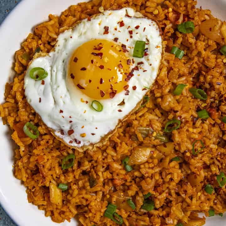 A beautiful fried egg on top of a bowl of spicy kimchi fried rice