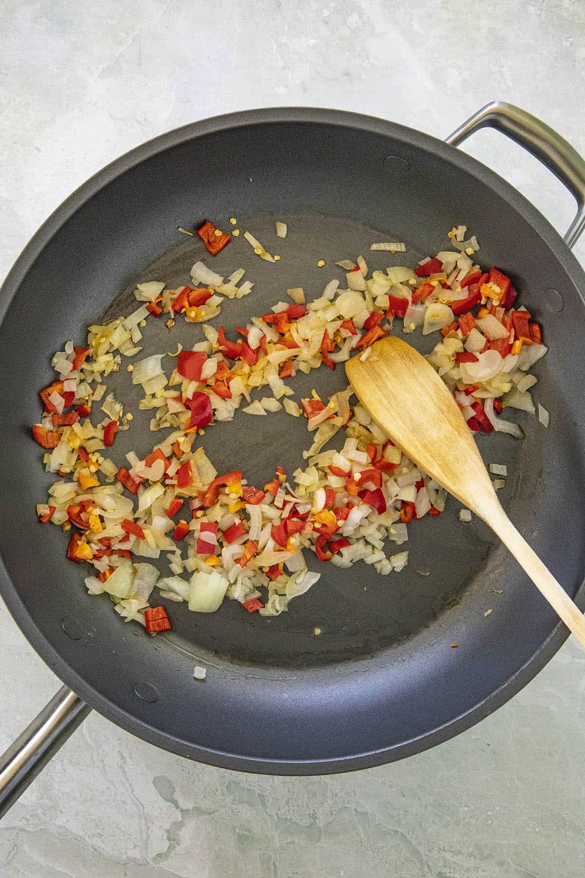 Mike cooking peppers and onions in a hot pan to make Arrabbiata Sauce