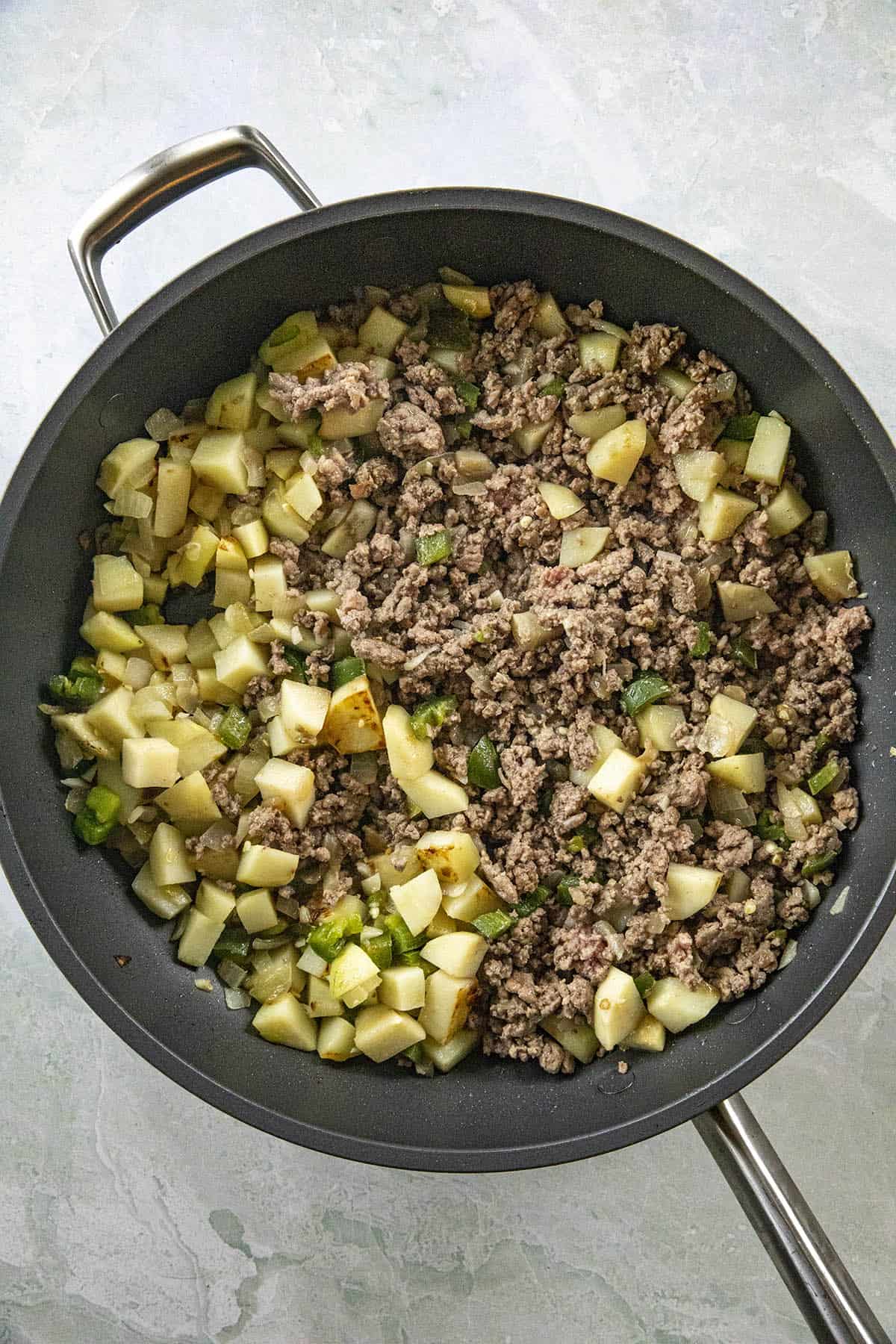 Cooking ground beef, peppers and potatoes to make Mexican Picadillo