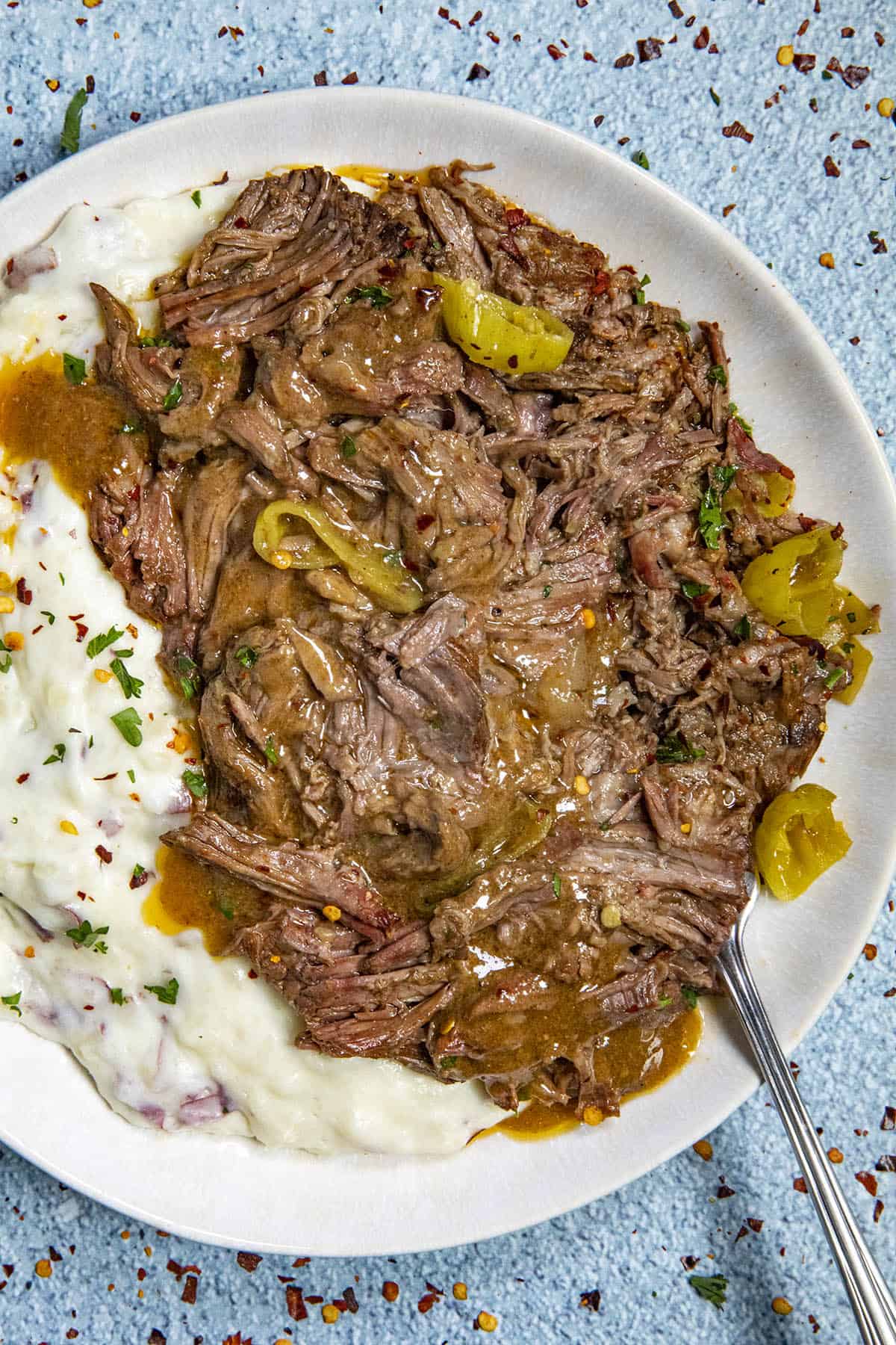Mississippi Pot Roast on a plate with mashed potatoes and extra gravy