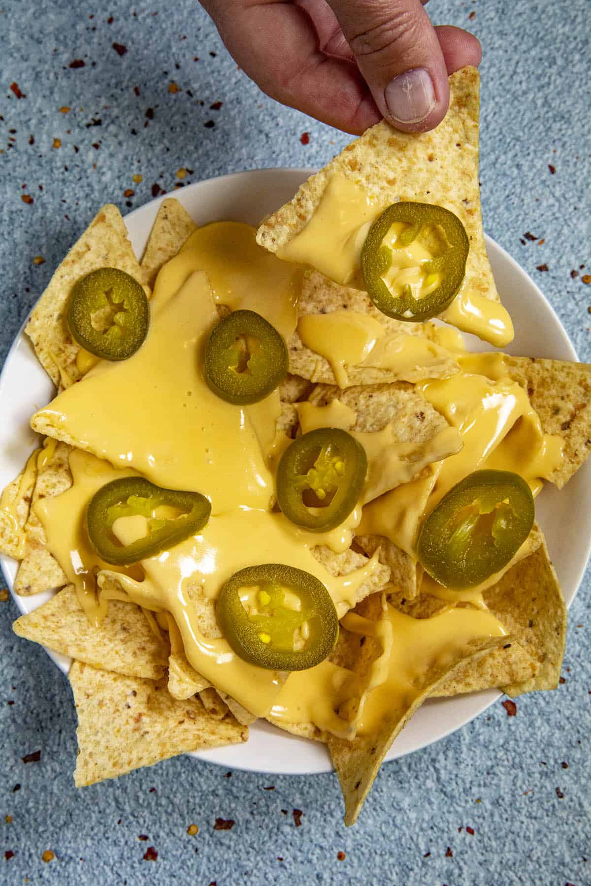 Mike taking a scoop of nachos with lots of nacho cheese sauce and pickled jalapenos