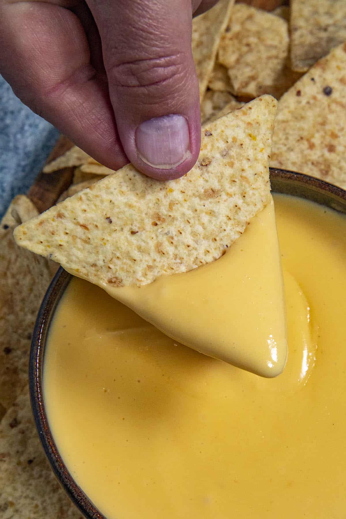 Mike scooping spicy Nacho Cheese Sauce onto a tortilla chip