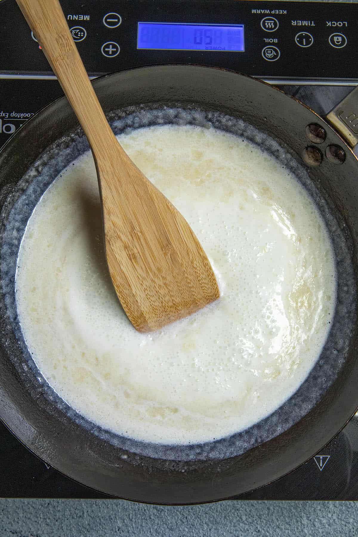Stirring milk into the roux to make spicy homemade Nacho Cheese Sauce
