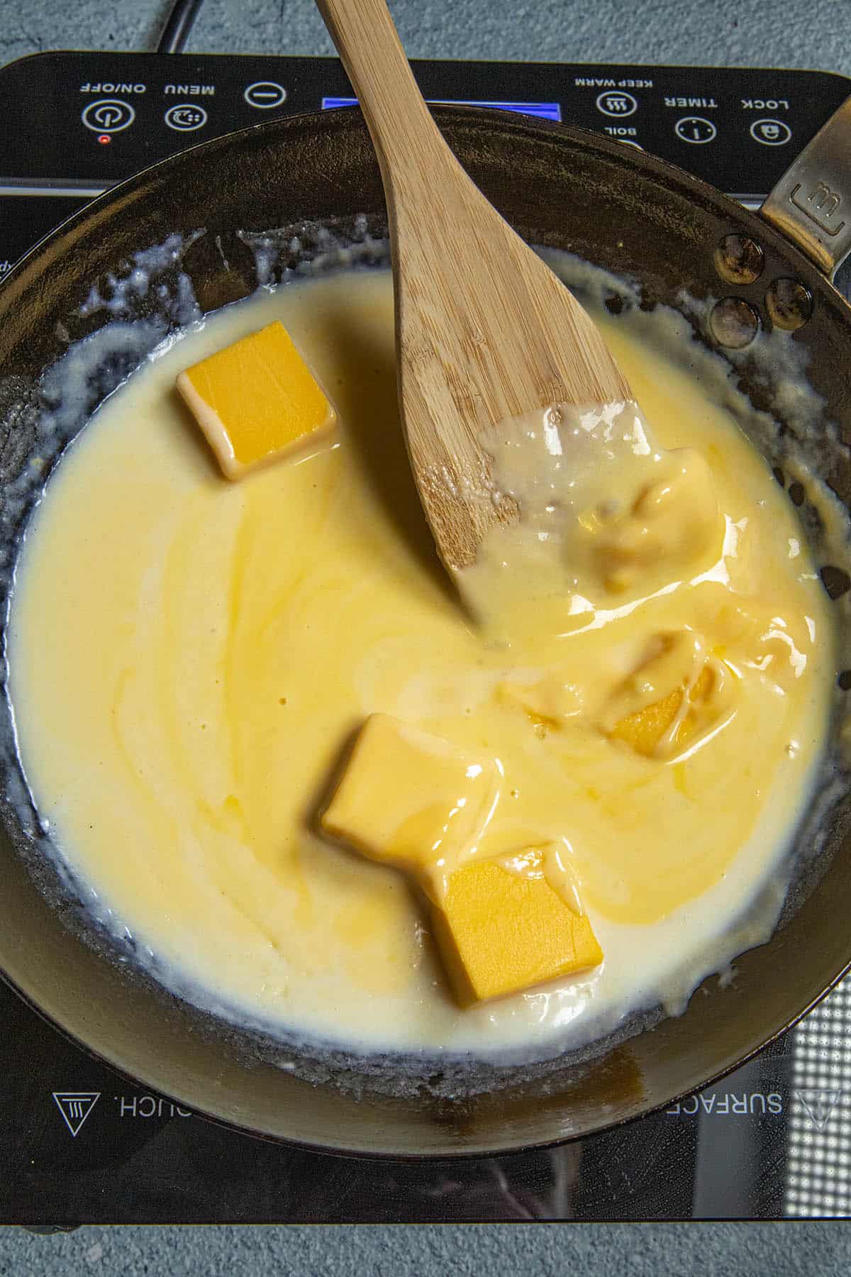 Stirring cheese into the spicy homemade Nacho Cheese Sauce