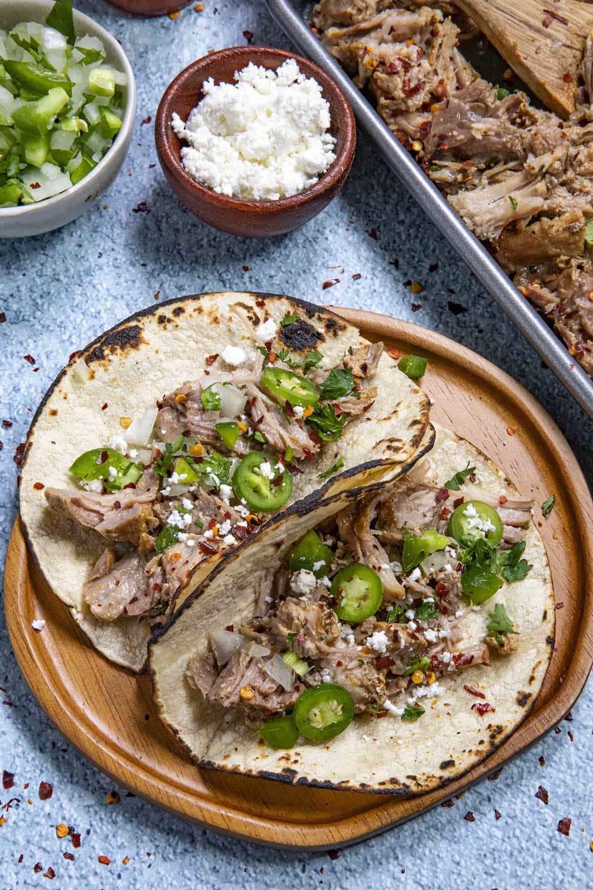 2 pork carnitas tacos on a plate with fixings, ready to enjoy