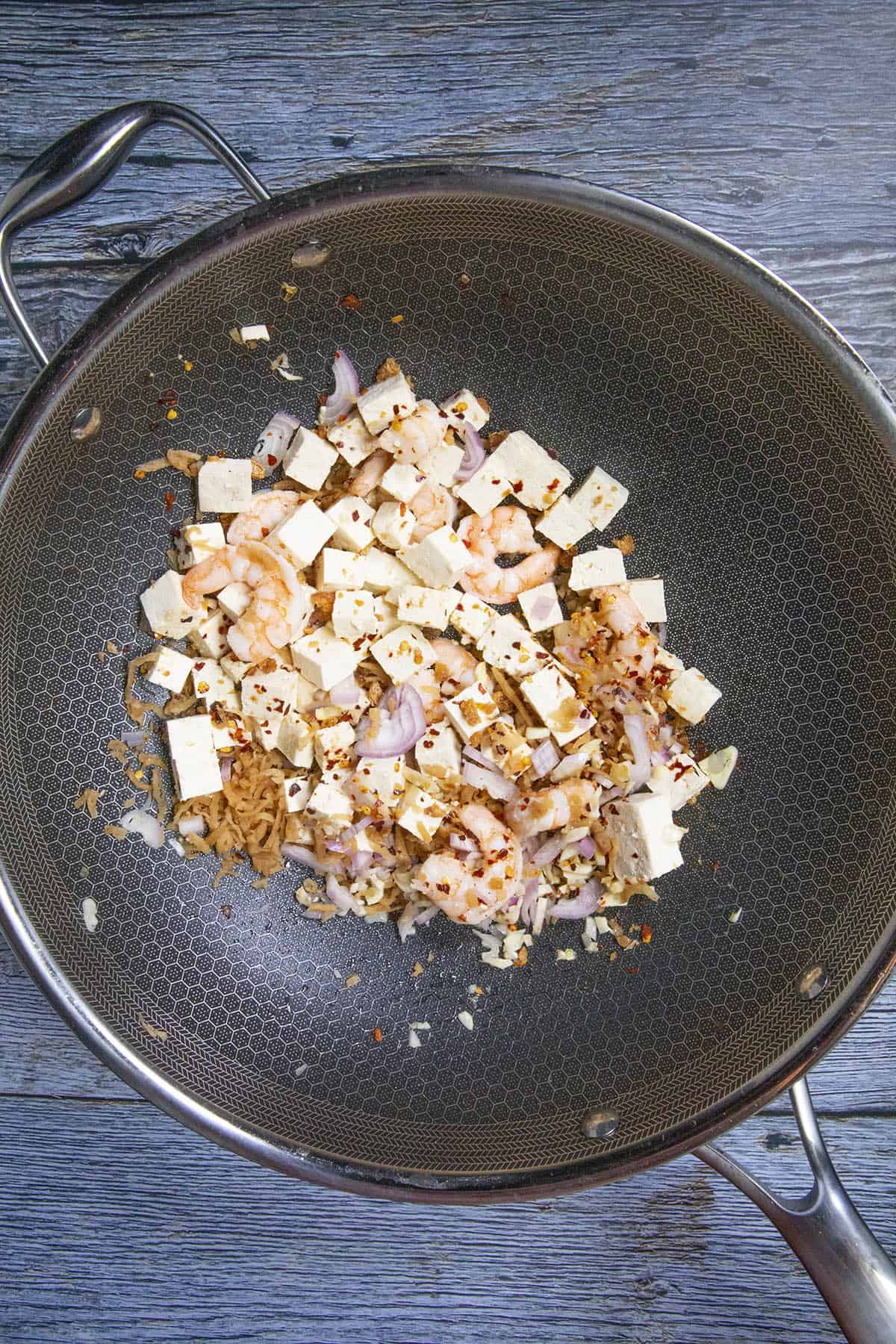 Stirring tofu and other ingredients in a pan to make Pad Thai