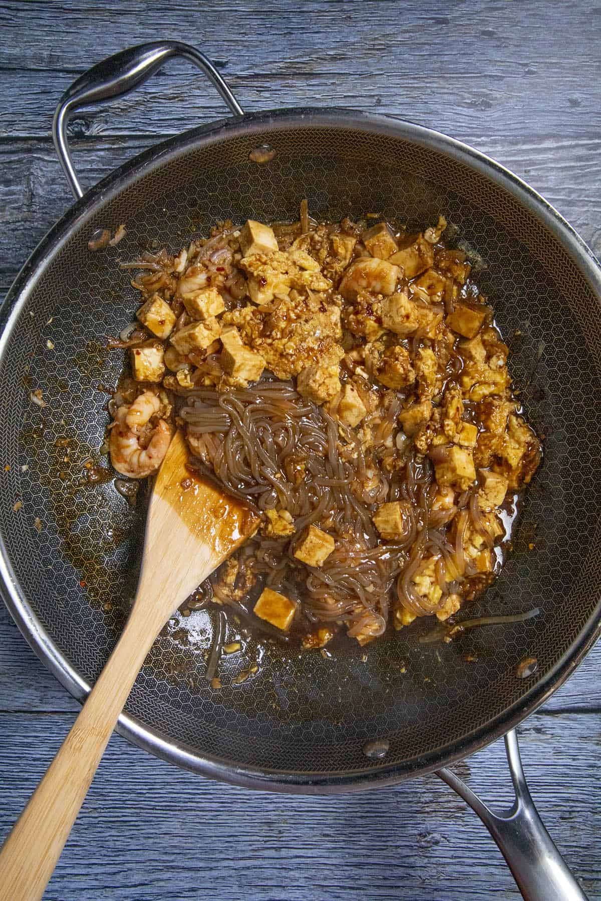 Stirring the noodles and sauce into the pan of Pad Thai