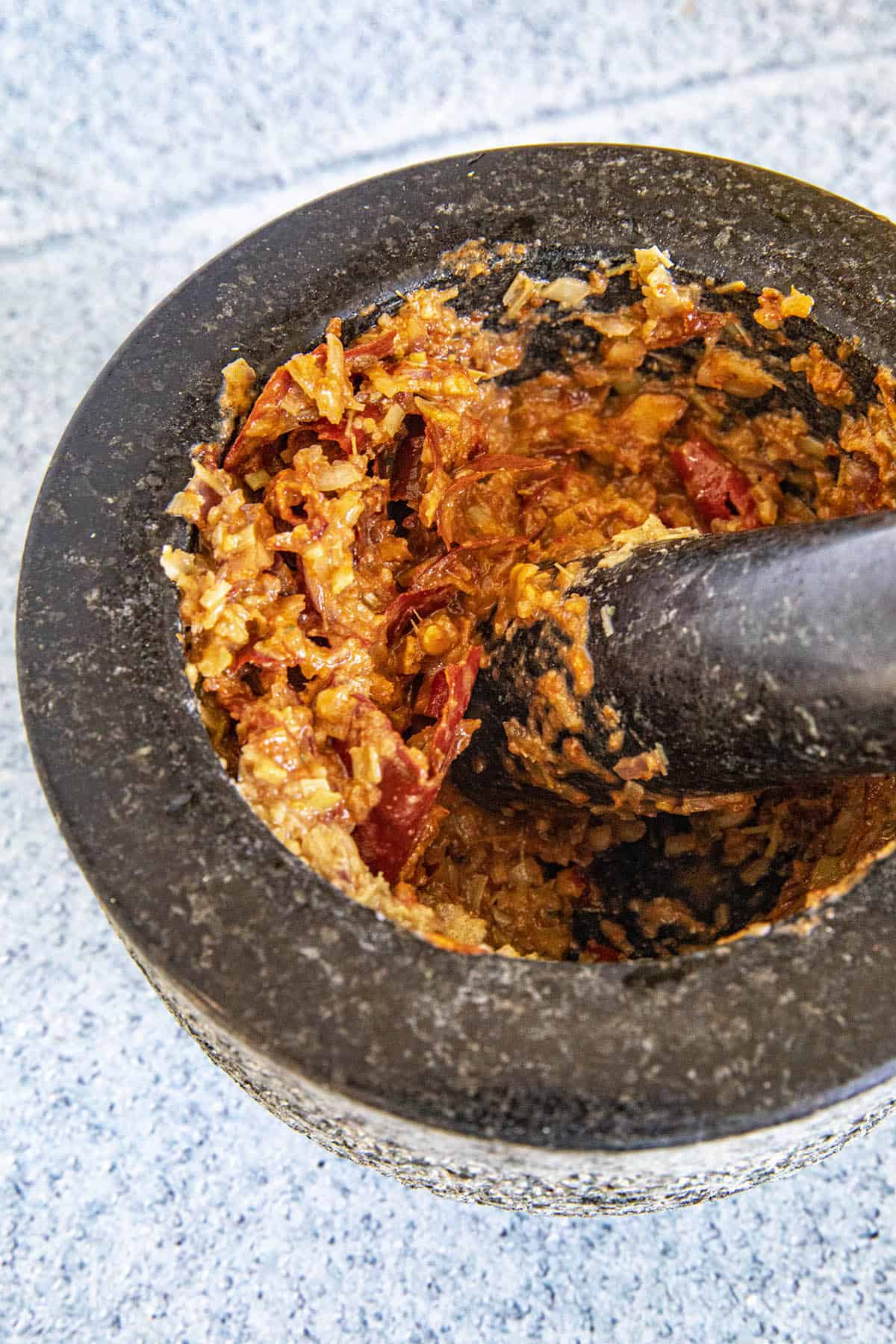 Grinding Panang Curry Paste ingredients in a grinding bowl