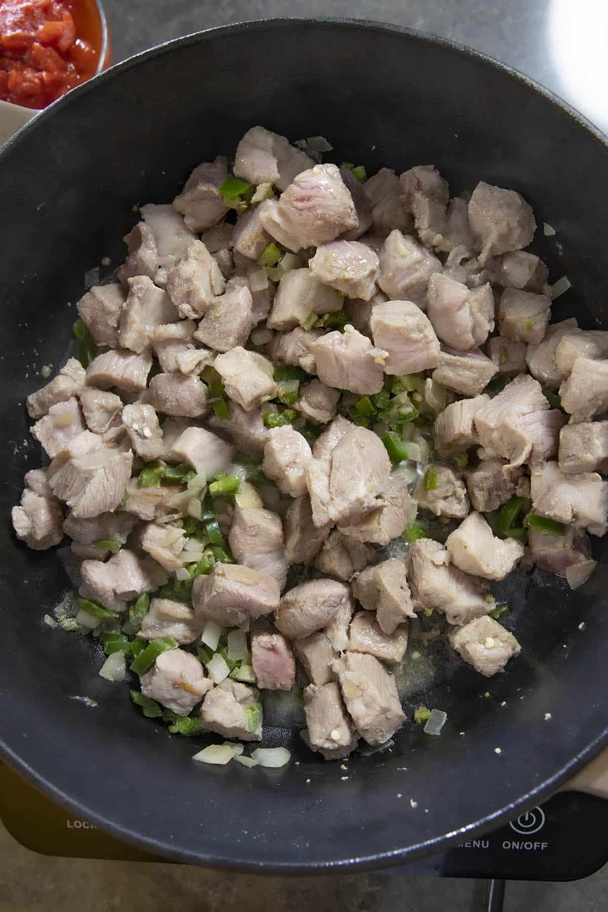 Cooking chopped pork shoulder and vegetables to make pork chili