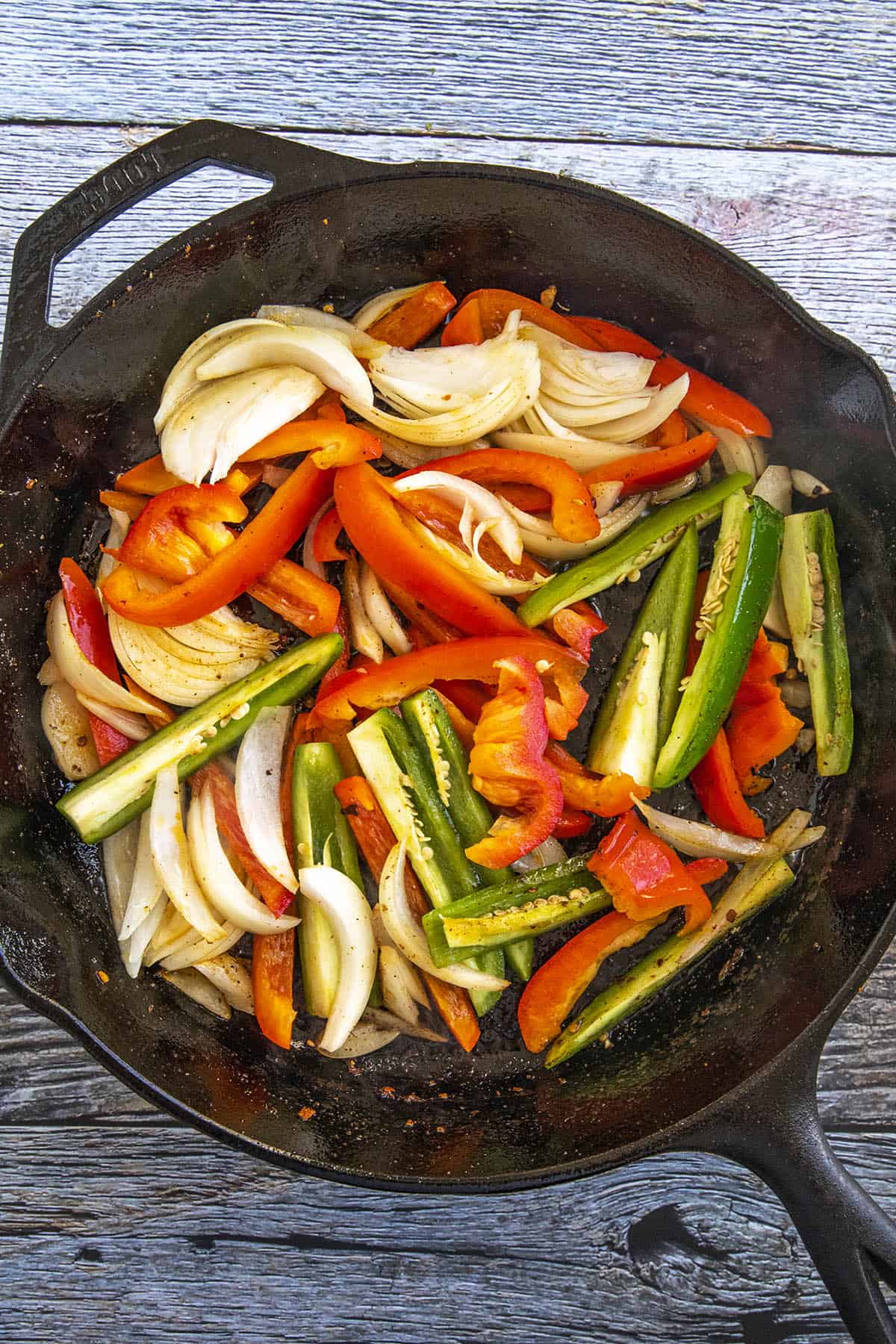 Cooking down peppers and onions in a hot pan