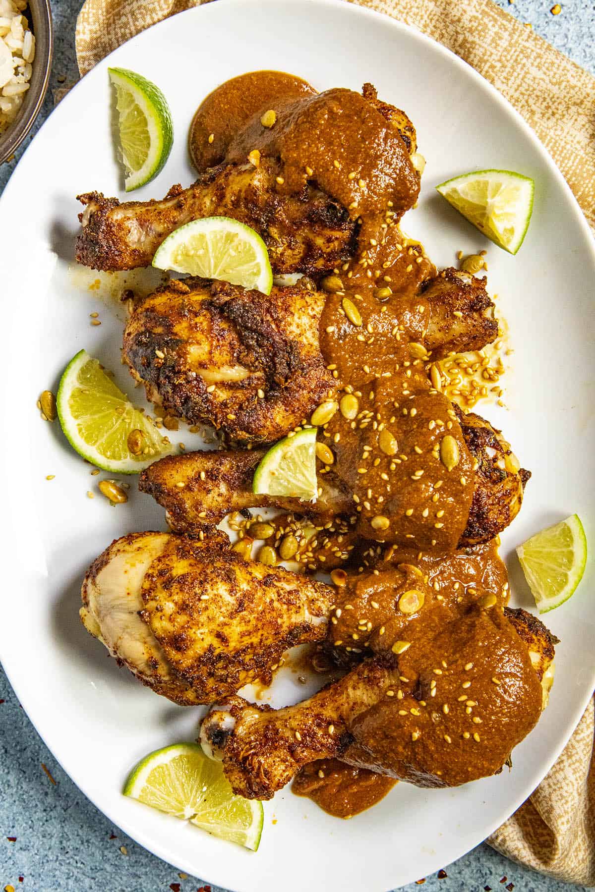 Chicken Drumsticks on a platter with Pipian Rojo and fresh limes