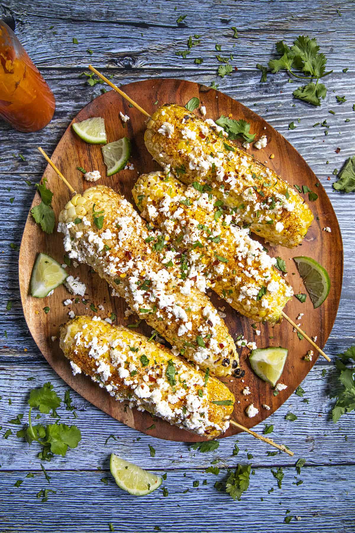 Elotes on a serving platter with lots of cheese and herbs