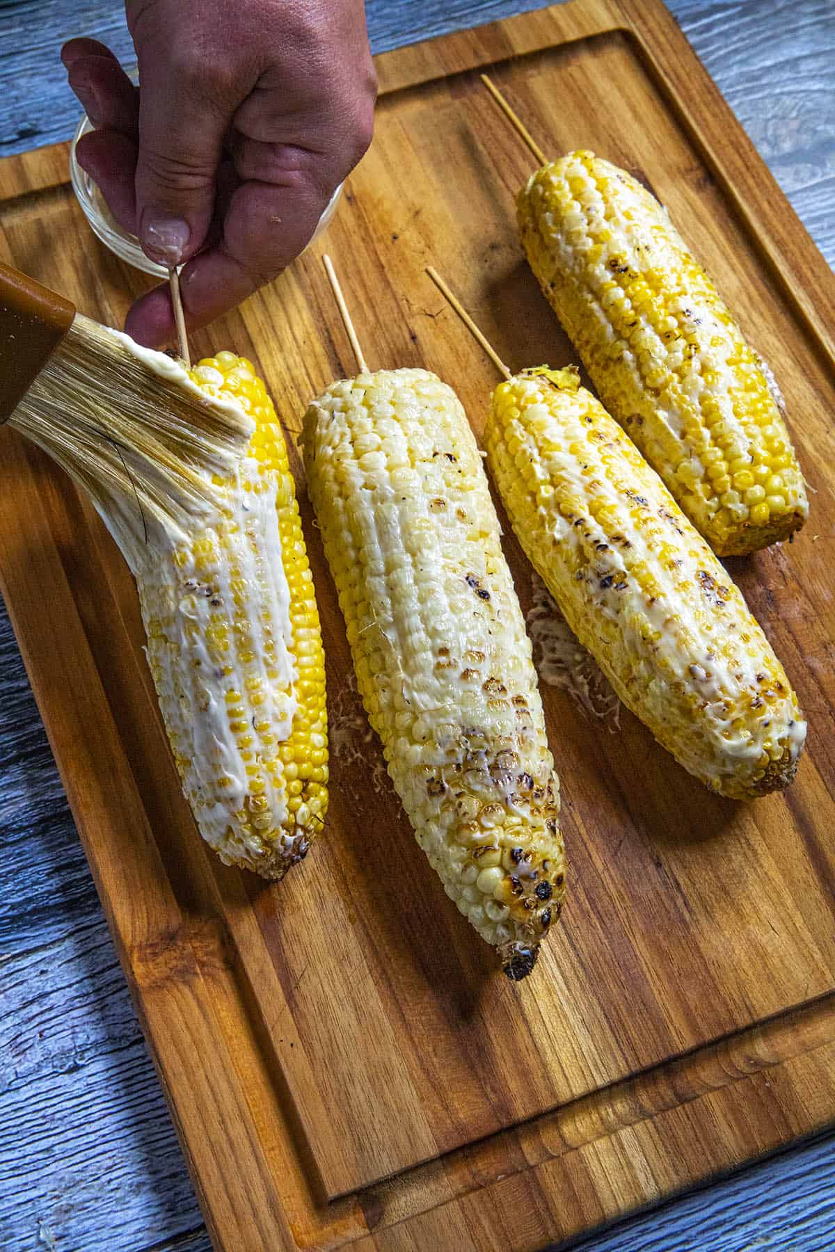 Coating the grilled corn with mayonnaise