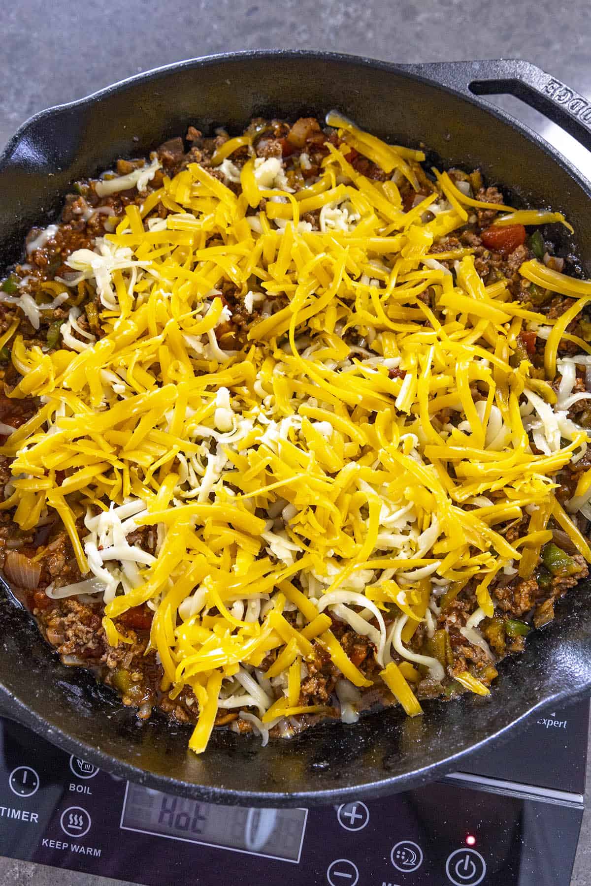 Topping the Chili Cheese Dip with cheese
