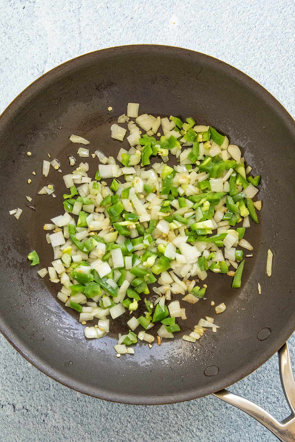 Cooking peppers and onions in a pan to make Mexican lasagna