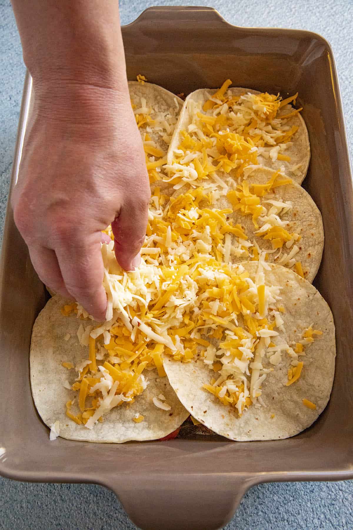 Sprinkling shredded cheese onto the Mexican Lasagna