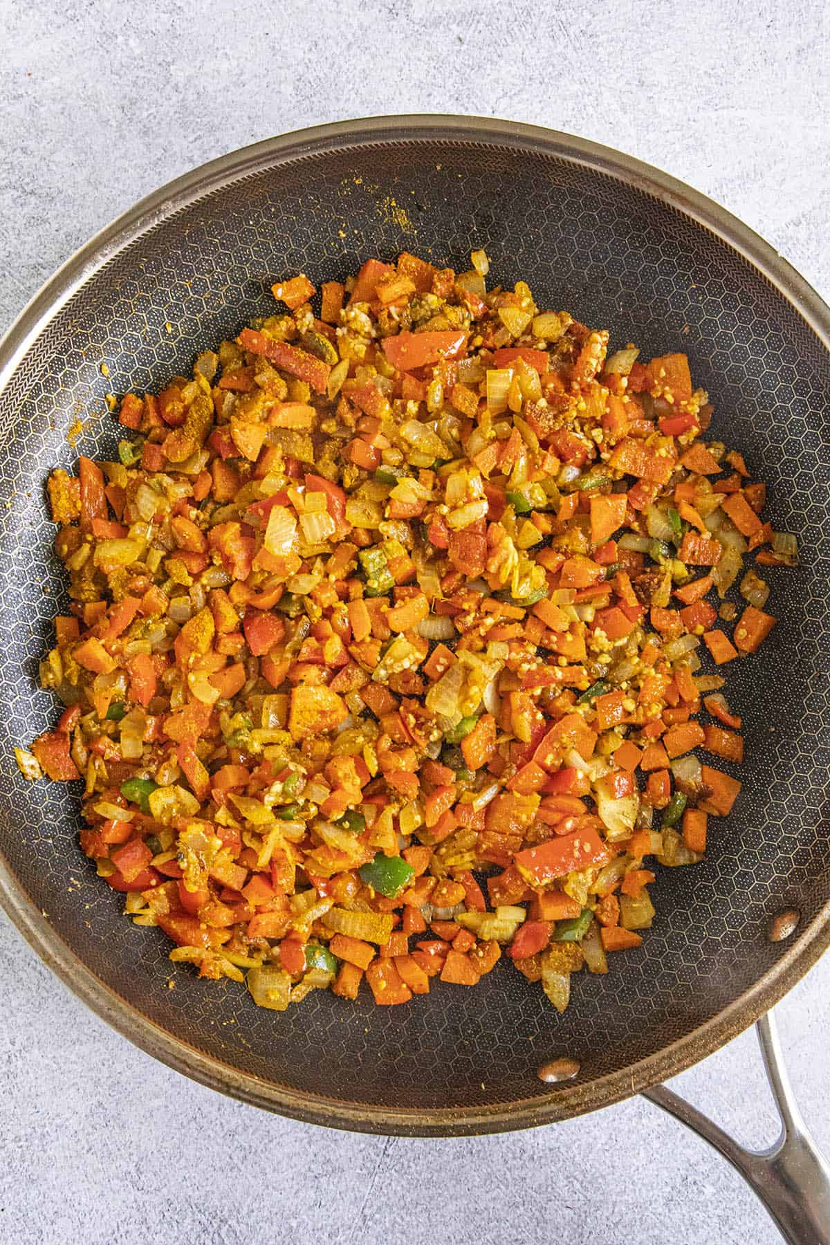 Cooking vegetables and spices in a pan to make Curried Rice